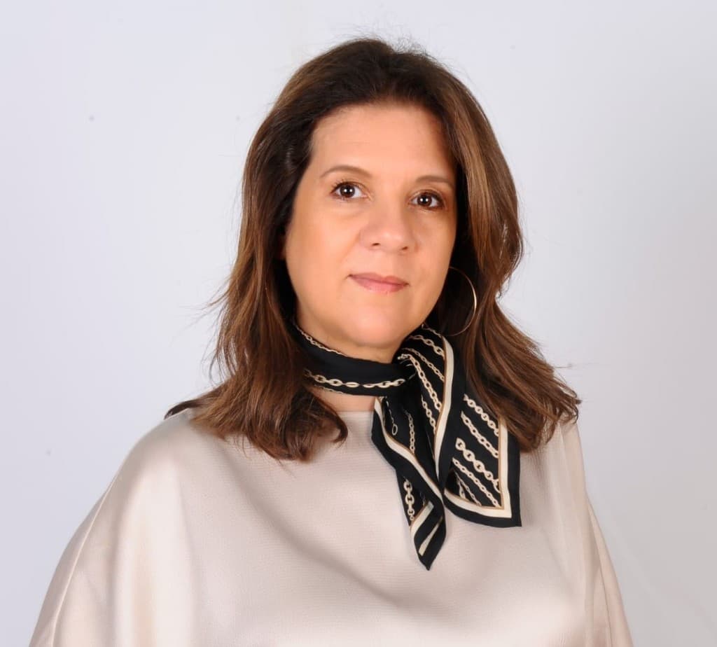 Portrait of Badia Dhrari, SOLA expert, in a champagne blouse against an off-white studio background